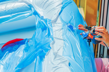 Close-up of female hands inflating a children's pool with an electric pump in the backyard of a...