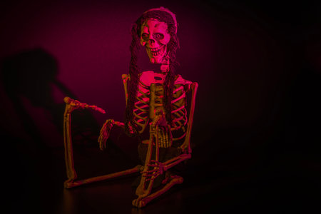 Grinning toy skeleton illuminated by red backlight against a black backdrop, capturing the essence of Halloween decoration. Sweden.の写真素材