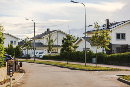 Picturesque European village with modern villas, asphalt road, and solar panels on rooftops, blending elegance with sustainability.の写真素材
