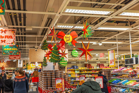 Christmas-decorated hypermarket grocery section with shoppers buying both holiday items and everyday...