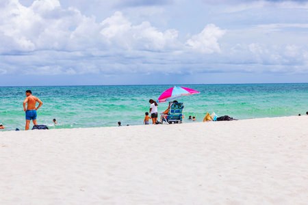 Beautiful view of sandy Miami Beach with people swimming in Atlantic Ocean and cloudy sky in background. Miami Beach. USA.のeditorial素材