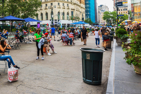 Busy city square in New York with people relaxing at outdoor tables and walking during warm summer day. New York. USA.のeditorial素材