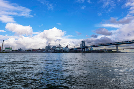Waterfront view of Brooklyn Bridge and New York skyline under cloudy sky. New York. USA.のeditorial素材