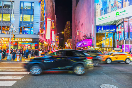 Busy street scene at night in Times Square with cars, pedestrians, and illuminated storefronts in New York City. USA.のeditorial素材
