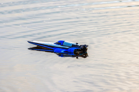 RC boat model standing still on calm water surface during peaceful day.