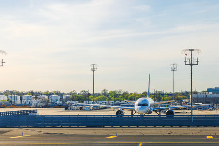 Airplane taxis down runway at Newark Liberty International Airport (EWR) with airport infrastructure and cargo containers in background. New York. USA.のeditorial素材