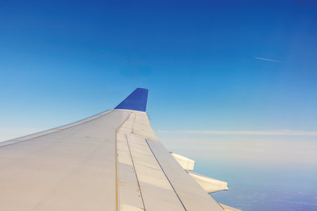 View from airplane window showing wing against clear blue sky during flight.の写真素材