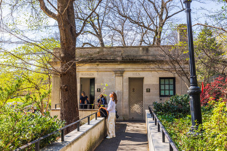 Visitors at public restroom in Central Park, surrounded by spring foliage and natural greenery on sunny day. New York. USA.のeditorial素材