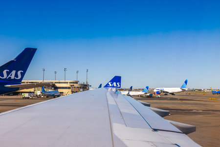 SAS plane parked at Newark Liberty Airport in New Jersey, with United Airlines planes visible under clear blue sky. New Jersey. USA.のeditorial素材
