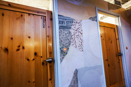 Wooden doors with "Harlem" and "Fidi" labels inside Levi's boutique against creative wall decor featuring fabric patterns. New York. USA.のeditorial素材
