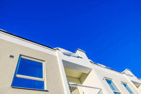 Modern building residential facade with snow-covered roof and bright blue sky on sunny winter day. Sweden.の写真素材