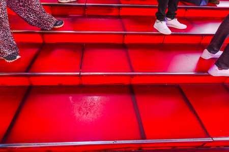Close-up view of illuminated red steps with people wearing casual shoes at night in Times Square, New York City. USA.の写真素材
