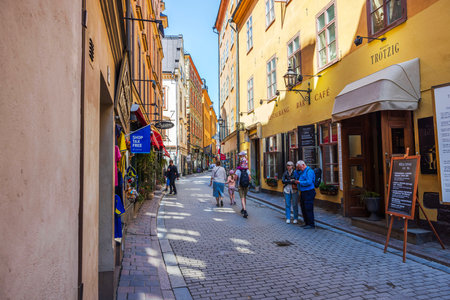 Charming cobbled street in Stockholm's old town with people strolling past colorful buildings, cafes and souvenir shops. Sweden. Stockholmのeditorial素材