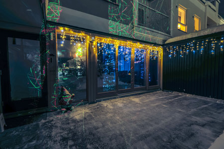 Festive house exterior with colorful lights reflecting on windows during snowy winter evening.の写真素材