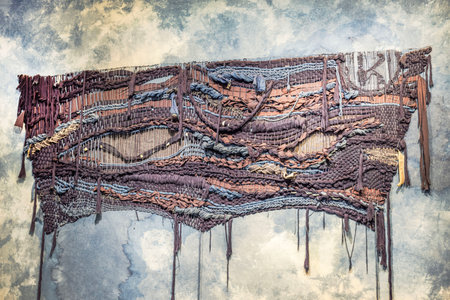 Handwoven textile art installation with intricate patterns of fabric, yarn and rope on textured background. USA.の写真素材