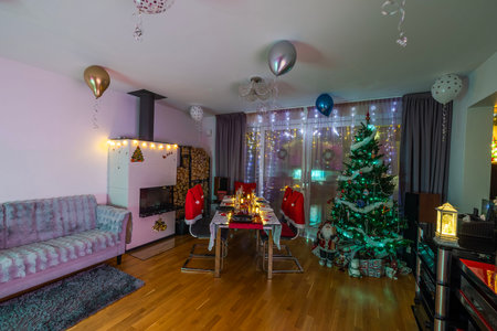Cozy living room with Christmas decorations, glowing lights, and festive atmosphere during winter holidays.の写真素材
