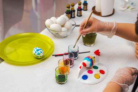 Child painting Easter egg on a special holder designed for kids, showcasing creativity and festive preparation. Sweden.の写真素材
