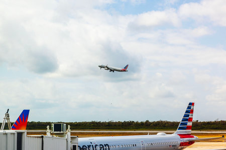 American Airlines plane taking off into cloudy sky near airport terminal. Cancun. Mexico.のeditorial素材