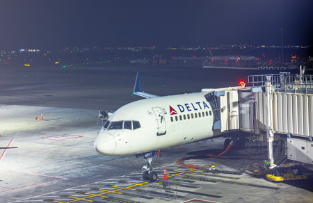 Delta Airlines plane docked at gate at Newark Liberty International Airport during nighttime operations. New Jersey, USA.のeditorial素材