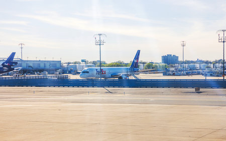 FedEx cargo planes parked on tarmac at busy airport during clear sunny day with ground equipment nearby. New Jersey, USA.のeditorial素材