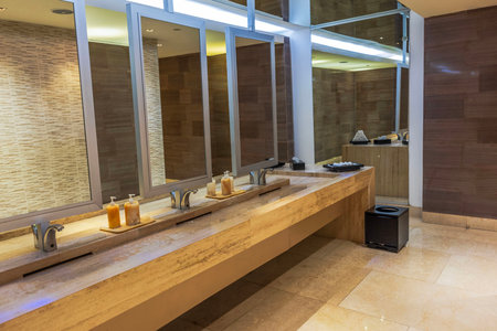 Luxury hotel restroom interior with marble sinks, modern mirrors, and soap dispensers reflecting sleek design.の写真素材