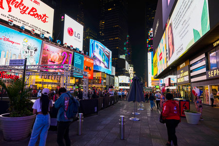 Street-level view of bustling Times Square at night with illuminated billboards, colorful advertisements and lively pedestrian activity. New York. USA.のeditorial素材