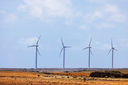 Wind turbines in desert landscape with clear blue sky, rocky terrain and bright sunlight.の写真素材