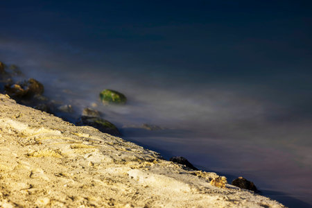 Close-up view of night sandy beach shoreline with small rocks and tranquil Caribbean Sea water, Aruba.の写真素材