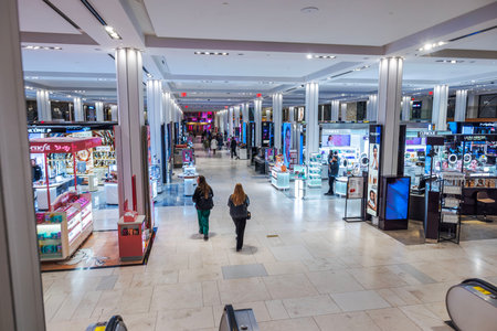 Brightly lit Macy's cosmetics section with luxury beauty brand counters, illuminated displays and shoppers. New York. USA.のeditorial素材