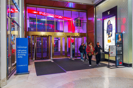 Entrance to Macy's Broadway location featuring illuminated signage, glass revolving doors and customers exiting under vibrant lighting. New York. USA.のeditorial素材