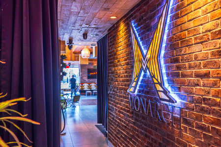 Illuminated Monarch logo on exposed brick wall at rooftop bar of Monarch hotel with warm lighting and stylish decor. New York. USA.のeditorial素材