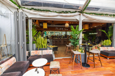 Modern rooftop bar with tropical plants, stylish seating and open interior design overlooking city skyline under glass roof. New York. USA.のeditorial素材