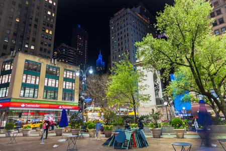 Night view of Herald Square in New York City with illuminated skyscrapers, green trees, outdoor seating and urban ambiance. New York. USA.のeditorial素材