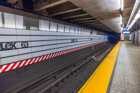 Lex 63 subway station platform in New York City featuring clean tiled walls, bright yellow safety strip, and empty tracks. New York. USA.のeditorial素材