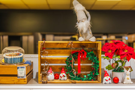 Festive Christmas display with red poinsettia, green wreath, holiday gnomes, and cake in wooden crates.のeditorial素材