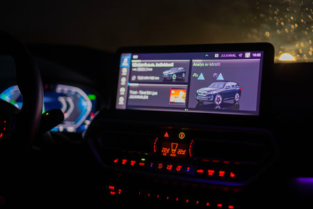 Close-up view of illuminated dashboard and digital display of BMW electric car at night, showing driving analysis and energy consumption data.のeditorial素材