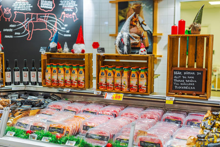 Festively decorated supermarket counter with assorted meat products, bottled gazpacho soup, wine bottles and Christmas gnome figurines.のeditorial素材