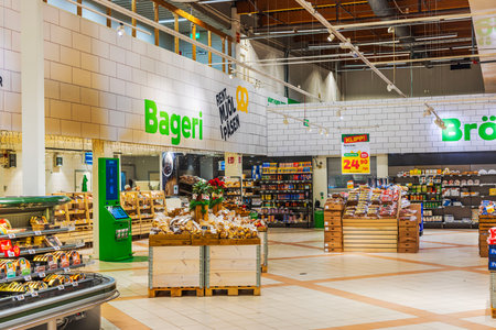 Bright bakery section in supermarket with fresh bread, pastries, and festive decorations under modern lighting.のeditorial素材