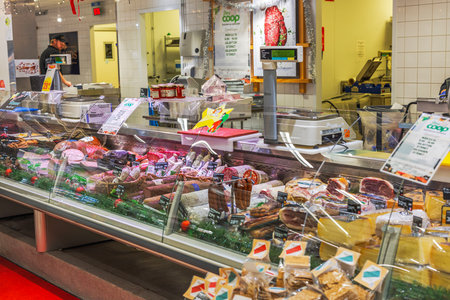 Deli counter with variety of sausages, ham, and premium meat delicacies displayed in grocery store.のeditorial素材