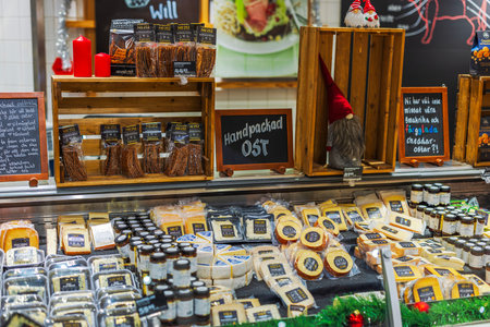 Cheese and snack display in grocery store with wooden shelves, packaged products, red candles and festive decorations.のeditorial素材