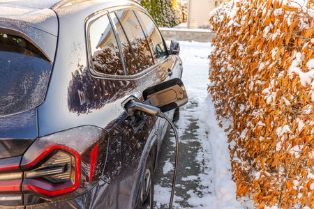 Close up view of electric car charging in parking lot of private villa outdoors in winter.の写真素材