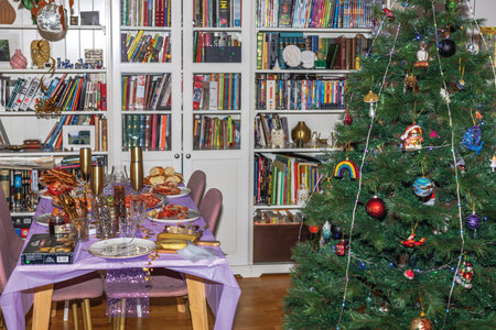 Festive dining table with elegant Christmas tree, colorful ornaments and delicious holiday meal in cozy home interior.のeditorial素材