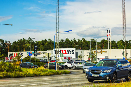 Exit road from shopping centers leading to highway with cars, traffic signs and surrounding green trees.のeditorial素材