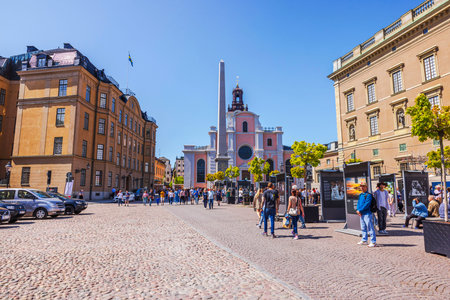 Crowded city square with historic buildings, Swedish flag and outdoor exhibition during Sweden's National Day celebration. Sweden. Stockholm.のeditorial素材