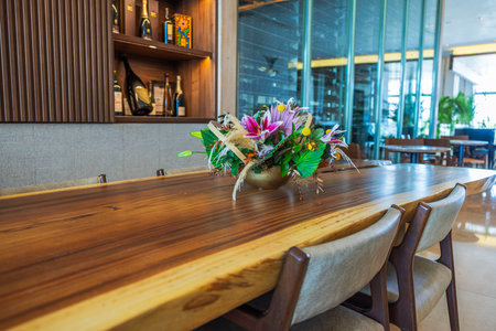 Decorative floral arrangement on wooden table in modern hotel interior with wine shelf background.の写真素材