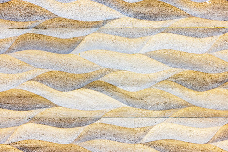 Abstract sand-colored textured wall with wave pattern design creating natural and artistic...