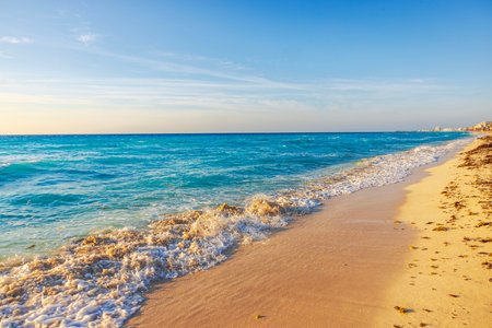 Golden hour view of sandy beach and turquoise waves along the Caribbean coast in Cancun, Mexico.の写真素材