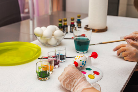 Mother teaching child to paint Easter egg using specialized rotating egg painting device with colorful dyes on table. Sweden.の写真素材