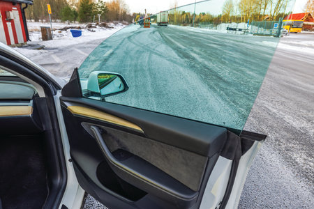 Open car door revealing modern interior design and clear glass window against snowy backdrop.の写真素材