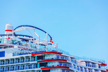 Close-up view of cruise ship deck with an outdoor roller coaster and modern balconies against blue sky. Curacao.の写真素材